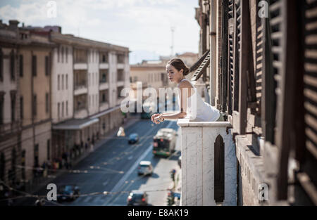 Jeune femme à la recherche sur balcon sur rue, Castiadas, Sardaigne, Italie Banque D'Images