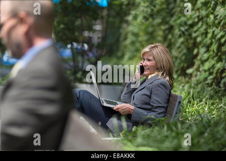 Mature businesswoman on phone with laptop Banque D'Images