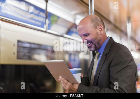 Man on Subway train holding digital tablet Banque D'Images