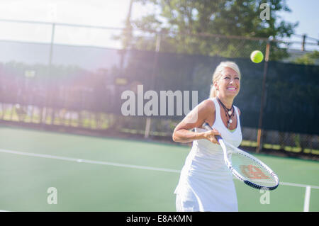 Smiling mature woman playing tennis Banque D'Images