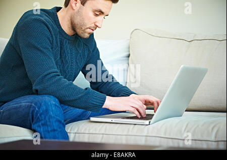 Man using laptop on sofa Banque D'Images