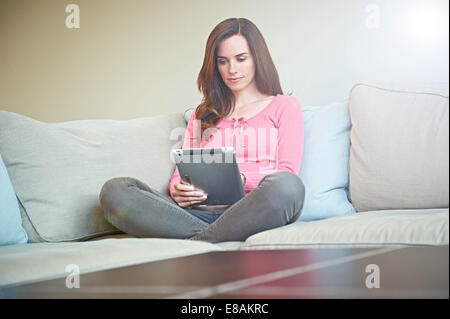 Woman using digital tablet on sofa Banque D'Images