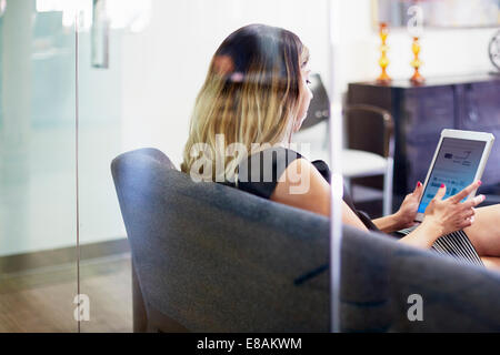 Young woman on sofa using tablet Banque D'Images