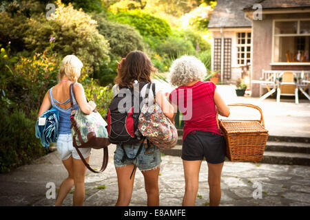 Vue arrière de la mère mature et deux filles de la marche avec sac à dos et panier pique-nique Banque D'Images