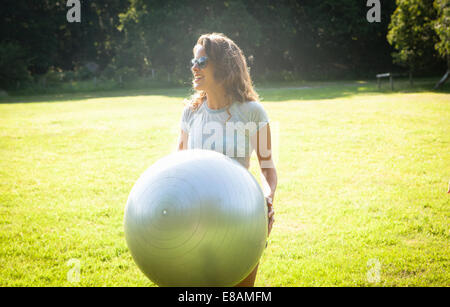 Mid adult woman holding up boule d'exercice dans le champ Banque D'Images