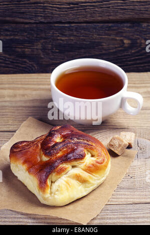 Petit pain sucré et une tasse de thé sur la table en bois Banque D'Images