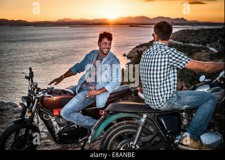 Portrait de deux hommes amis motocyclistes sur l'autre au coucher du soleil, Cagliari, Sardaigne, Italie Banque D'Images