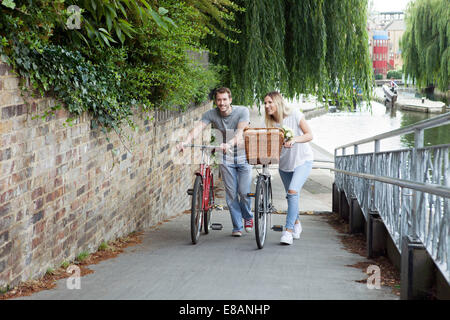 Couple cycliste poussant vélo le long canal, London, UK Banque D'Images