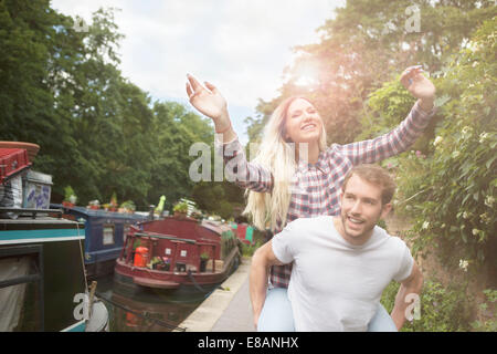 Couple playing piggyback par canal, East London, UK Banque D'Images