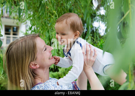 Mother holding up baby fille face à face au jardin Banque D'Images