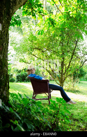 Mid adult woman asleep en fauteuil de jardin Banque D'Images