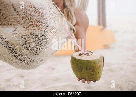 L'eau de coco Man enjoying in hammock on beach Banque D'Images