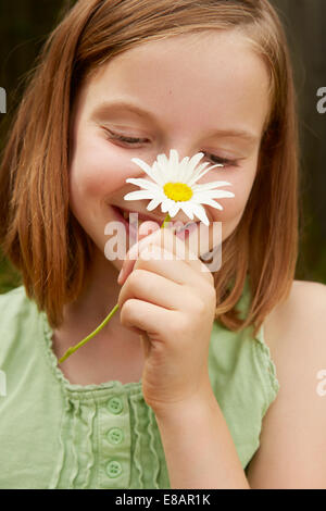 Portrait of Girl in garden holding up daisy Banque D'Images