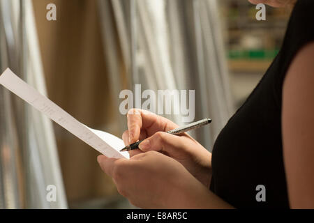 Close up of female warehouse worker taking stock in hardware store Banque D'Images