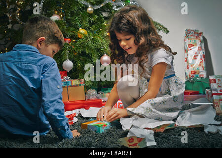 Frère et soeur dans la salle de séjour unwrapping christmas gifts Banque D'Images