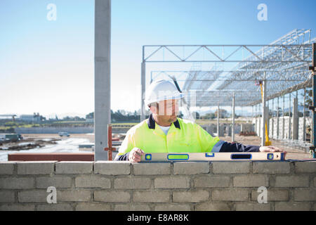 Builder en utilisant un niveau à bulle sur le site de construction mur Banque D'Images