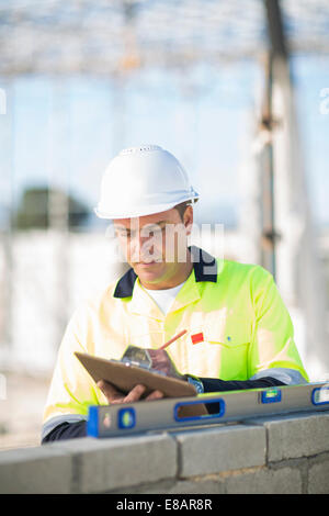 Site manager contrôle de niveau à bulle sur chantier wall Banque D'Images