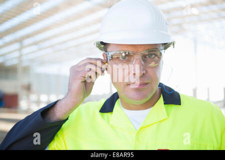 Builder avec des lunettes de sécurité l'insertion des bouchons d'on construction site Banque D'Images