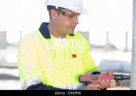 Builder en utilisant la perceuse électrique on construction site Banque D'Images