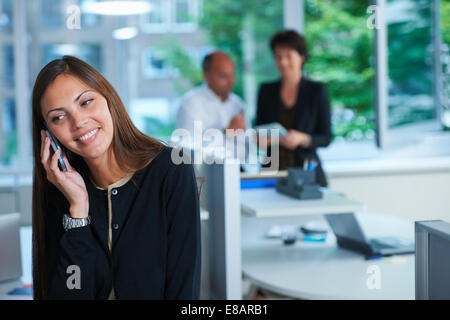 Businesswoman chatting on smartphone in office Banque D'Images