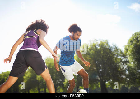 Jeune couple playing soccer in park Banque D'Images