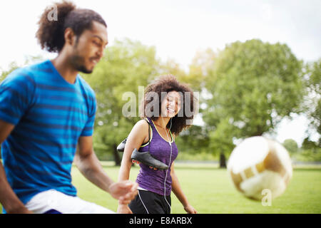 Jeune couple playing soccer keepy uppy in park Banque D'Images