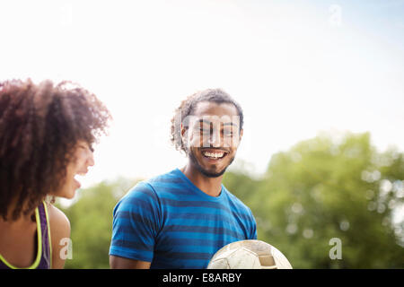 Football jeunes couple chatting and laughing together in park Banque D'Images