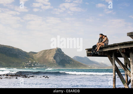 Jeune couple assis sur le bord de l'ancienne jetée, Cape Town, Western Cape, Afrique du Sud Banque D'Images
