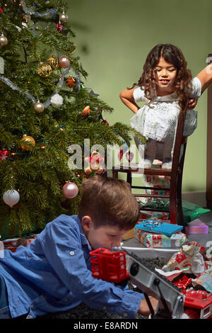 Soeur frère en regardant déballer et jouer avec les cadeaux de Noël Banque D'Images