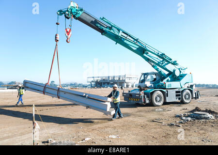 Deux constructeurs guider poutres sur crane at construction site Banque D'Images