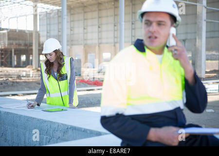 Site manager chatting on smartphone sur chantier Banque D'Images