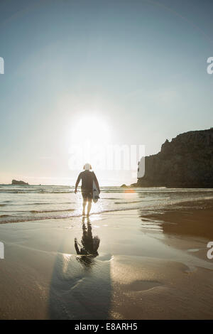 Femme marchant vers la haute mer avec surfboard, Camaret-sur-mer, Bretagne, France Banque D'Images