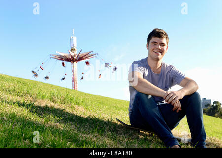 Portrait of young man sitting on skateboard Banque D'Images