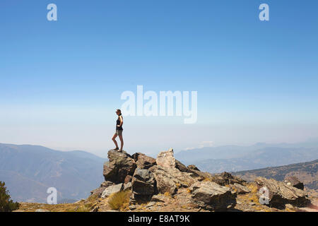 Jeune femme debout sur le haut des roches à regarder vue, Sierra Nevada, Grenade, Andalousie Espagne Banque D'Images