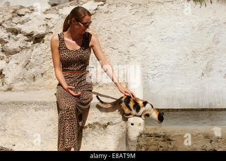 Young woman leaning against wall petting cat, Sierra Nevada, Grenade, Andalousie Espagne Banque D'Images