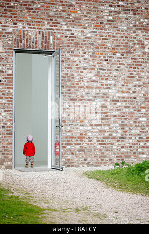 Young Girl standing in doorway en brick wall Banque D'Images