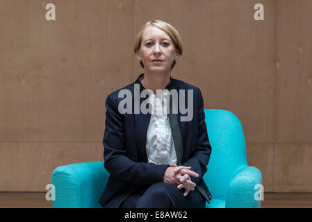 Une entreprise aux cheveux courts femme assise dans un fauteuil bleu couleur funky avec les jambes pliées dans un costume d'affaires dans une salle de réunion Banque D'Images