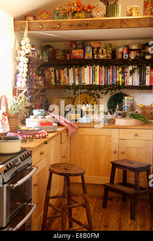 Tabourets en bois ancien en pays cuisine avec pin et de livres de cuisine sur les étagères en bois Banque D'Images