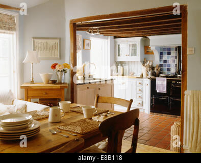 La vaisselle de table crème sur le pin gris pâle, salle à manger avec porte de cuisine avec Aga noir et une carrière de carrelage Banque D'Images