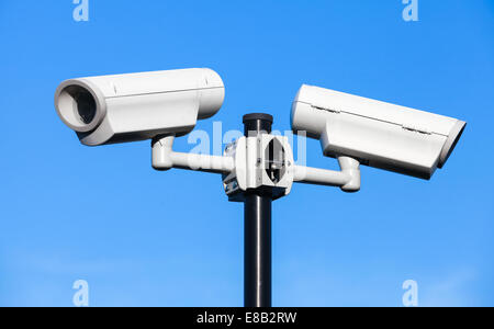 Deux caméras de télévision en circuit fermé monté sur poteau noir au-dessus de ciel bleu Banque D'Images