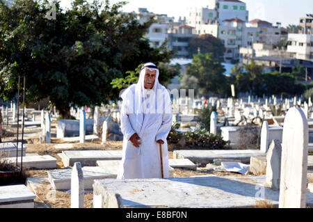 La ville de Gaza, bande de Gaza, territoire palestinien. 3e oct, 2014. Un Palestinien prie sur la tombe d'un parent dans un cimetière à la fête musulmane de l'Aïd al-Adha ou ou la fête du sacrifice, dans la ville de Gaza le 4 octobre 2014. Les musulmans du monde entier célèbrent l'Aïd al-Adha, la Fête du Sacrifice, pour marquer la fin du hajj pèlerinage en abattant les moutons, chèvres, vaches et chameaux pour commémorer le Prophète Abraham est prêt à sacrifier son fils Ismaël sur l'ordre de Dieu © Mohammed Talatene/APA/Images/fil ZUMA Alamy Live News Banque D'Images