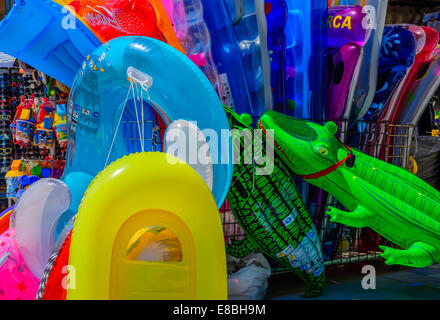 Deflatable colorés des jouets de plage, des lits flottants, des bateaux, des lunettes, des seaux et un couple de crocodiles dans un magasin avant sur une plage Banque D'Images