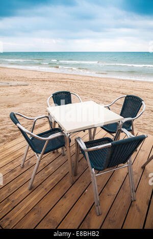 Espace ouvert côté mer bar intérieur avec plancher en bois et de fauteuils en métal sur la plage de sable Banque D'Images