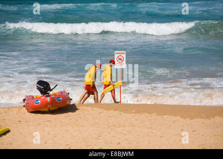 Surf Life Savers sauvetage deux adolescents sur Manly Beach, Sydney, Australie en passant devant les forts courants danger sign Banque D'Images