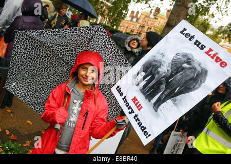 Londres, Royaume-Uni. 4e octobre 2014. Fille avec un parapluie et affiche de la Marche Mondiale pour les éléphants et rhinocéros, Londres, Angleterre. Pluie n'a pas refroidir l'enthousiasme des marcheurs la prise de conscience de la situation critique des éléphants et rhinocéros qui entre autres choses sont tués par les braconniers pour l'ivoire et de souvenirs. Crédit : Paul Brown/Alamy Live News Banque D'Images