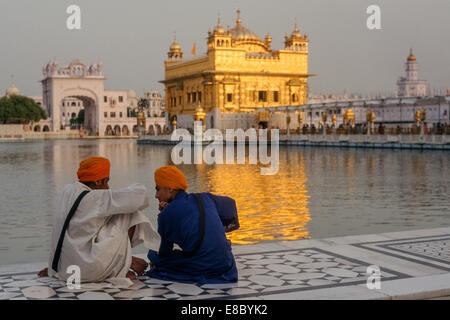 Deux jeunes hommes assis en face du Harmandir Sahib, ou Temple d'Or, l'un des sites les plus vénérés pour les Sikhs, Amritsar, Punjab, India Banque D'Images