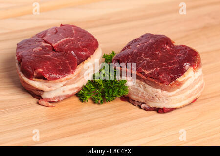 Filet mignon 8 oz deux steaks de bœuf enveloppé de bacon sur une planche à découper en bois. Banque D'Images