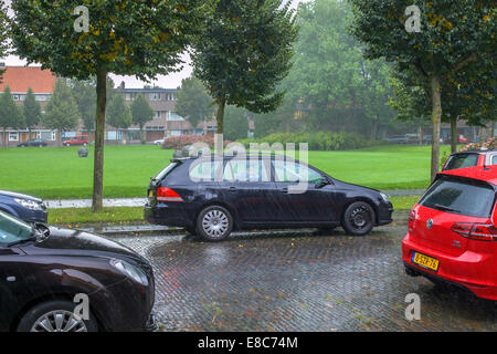 Garçon à l'intérieur d'une voiture sous la pluie dans une rue Banque D'Images