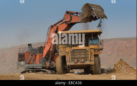 Une orange Hitatchi charges excavatrice stériles et de sol dans un camion minier Caterpillar dans une grande mine de cuivre de l'Afrique de l'ouvert. Banque D'Images