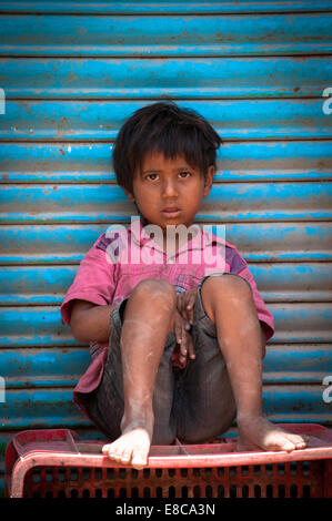 Seul pauvre innocent enfant indien assis sur une boîte sur le bord de la route Banque D'Images